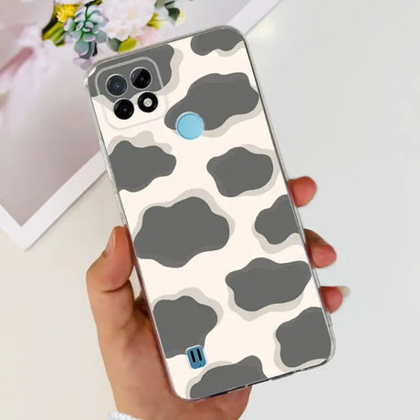 a woman holding a phone case with a cow print