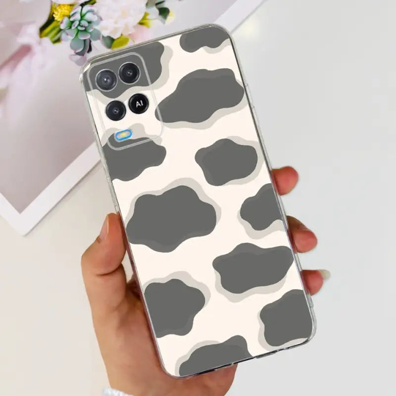 a woman holding a phone case with a cow print