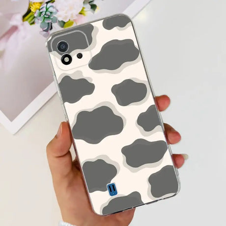 a woman holding a phone case with a cow print