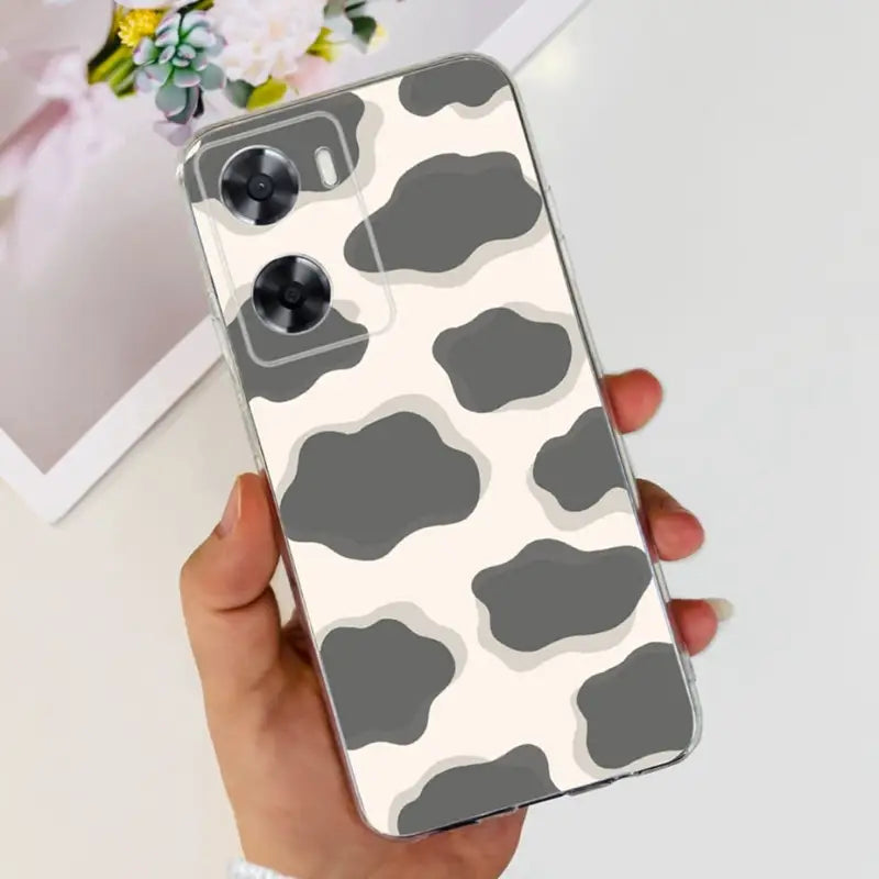 a woman holding a phone case with a cow print