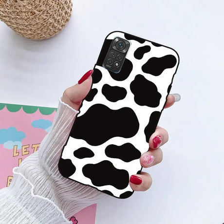 a woman holding a phone case with a cow print