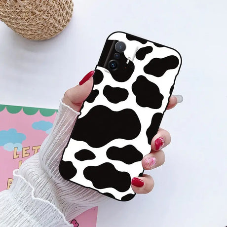 a woman holding a phone case with a cow print