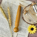 a glass jar with a wooden handle and a wooden spoon next to it