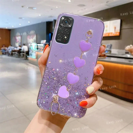 a woman holding a purple phone case with heart charms