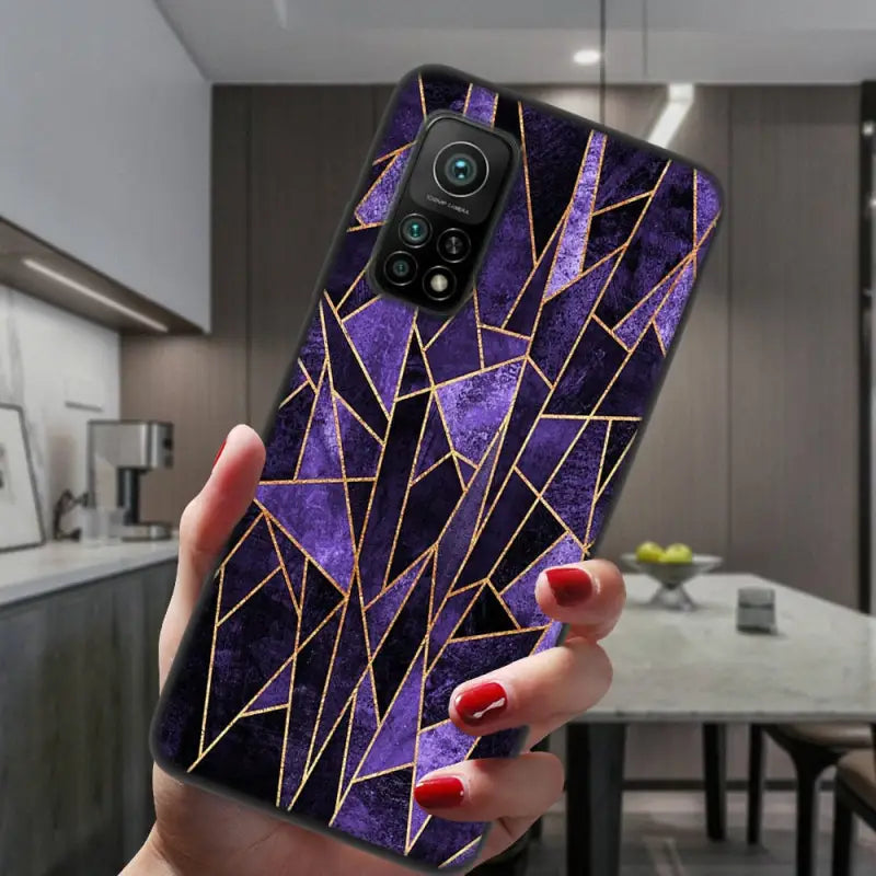 a woman holding up a purple phone case with gold triangles