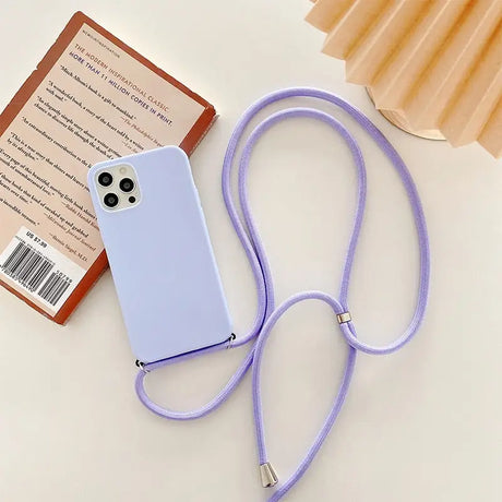 purple phone case with a lanyard attached to it next to a book