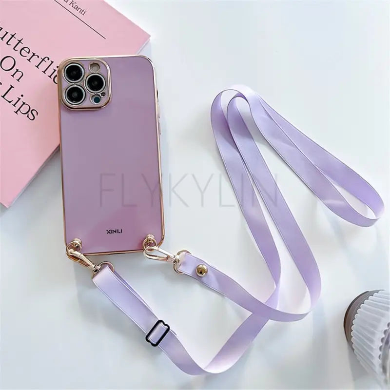 purple phone case with lanyard strap and a book