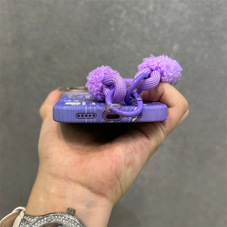 Purple phone case with pom-pom strap.