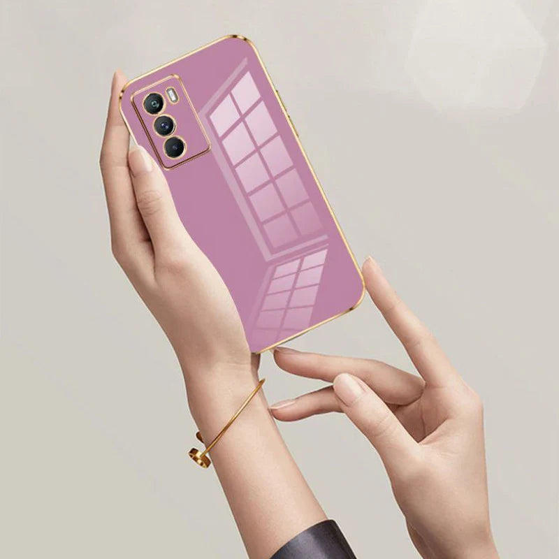 Purple smartphone with a gold-edged case and triple rear cameras held by hands.