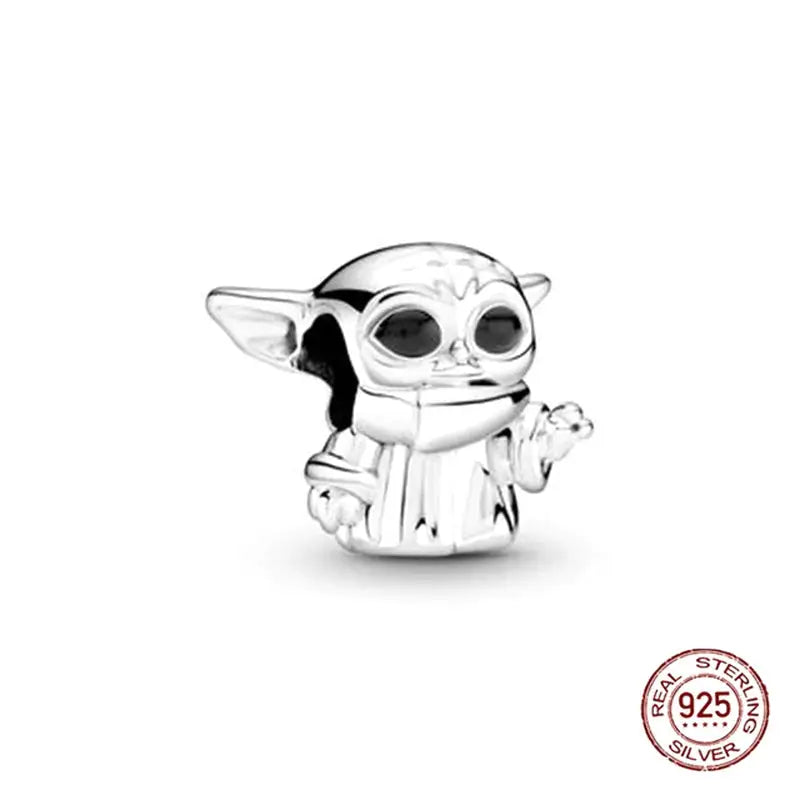 a silver charm with a baby yodah holding a star wars badge