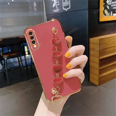 Red smartphone case with a decorative heart-shaped charm attachment.