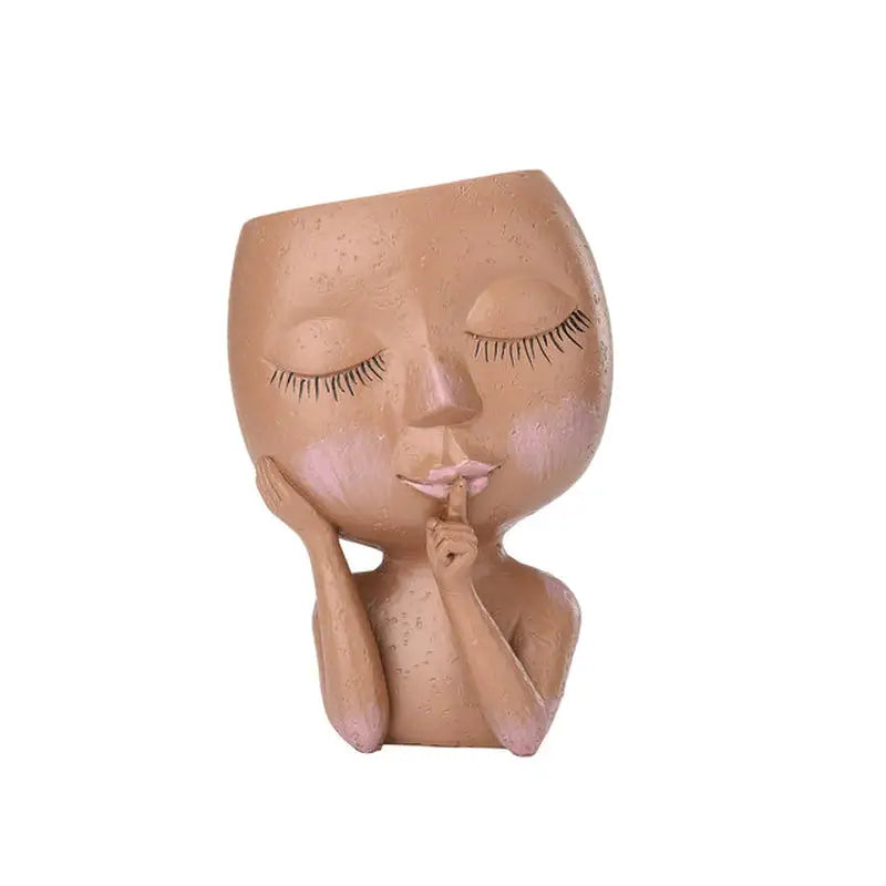 a clay sculpture of a woman’s face with her hand on her chin