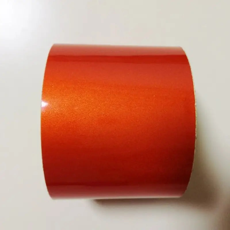 a roll of orange tape on a white surface