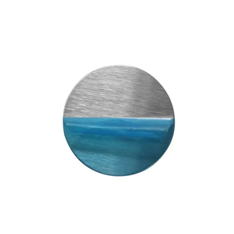 a round metal button with a blue ocean scene