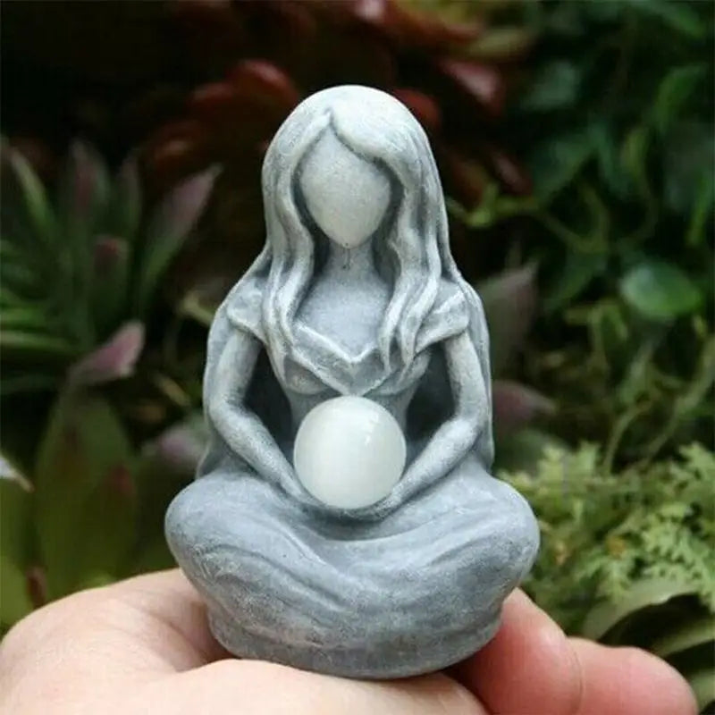 a small statue of a woman holding a white egg