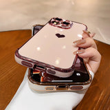 A shiny, pink iPhone case with a black heart design, a jeweled camera outline, and a metallic rose gold bumper.