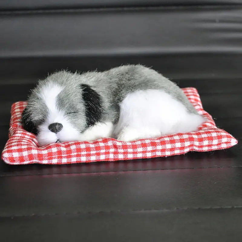 a small dog sleeping on a red and white blanket