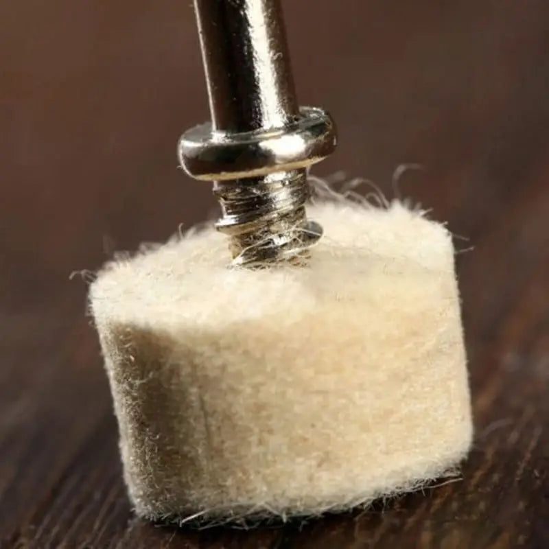 a small piece of white wool is being held by a metal needle