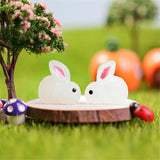 two white rabbits sitting on a wooden stump