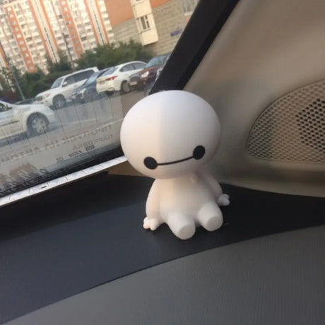 a small white stuffed animal sitting on the dashboard of a car