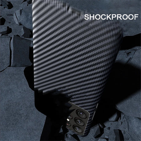 A smartphone with a black carbon fiber textured case featuring multiple camera lenses and ’SHOCKPROOF’ text.