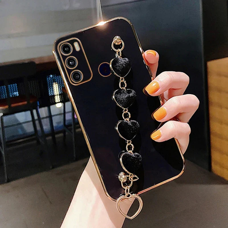 Smartphone with a black case featuring a decorative heart-shaped charm accessory.