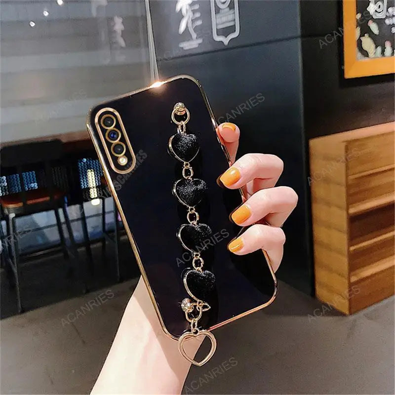 Smartphone case with a decorative chain attachment featuring heart-shaped charms.