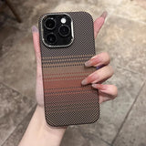 A smartphone with a checkered brown and black patterned case, featuring a camera module with three lenses and a flash, held by a hand with long, clear-to-pink gradient nails.