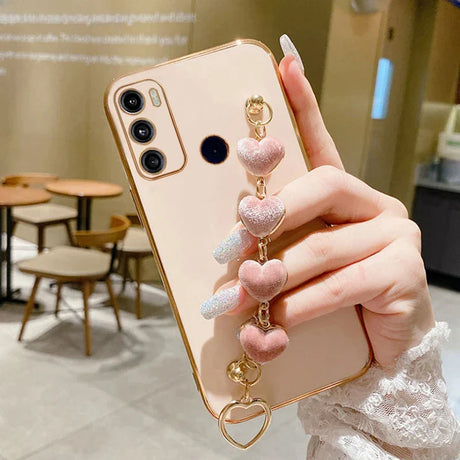 Smartphone with a gold-colored case and a decorative heart-shaped charm attached.