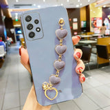 Smartphone with a lavender case and heart-shaped charm accessory attached.