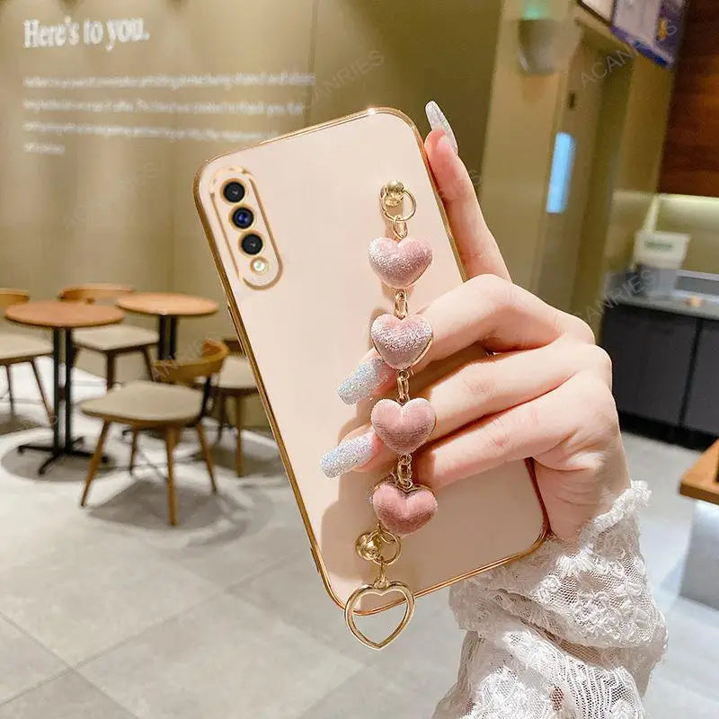 Smartphone with a pink heart-shaped charm attached to its case.