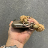 Smartphone in a protective case with a fuzzy charm.