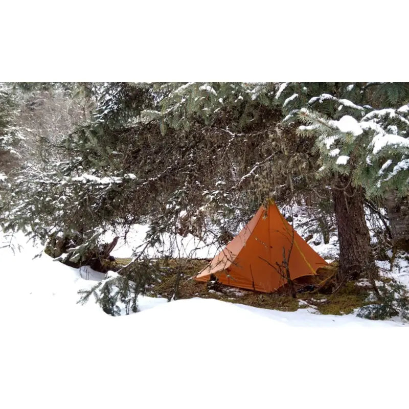 a tent in the snow with trees in the background