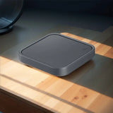 A square gray plastic container on a wooden table