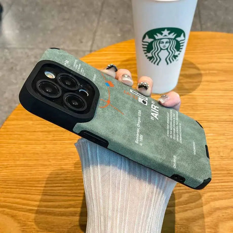 Someone holding a starbucks cup and a phone case on a table