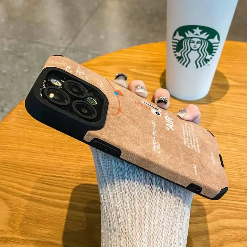 someone holding a starbucks cup and a phone case on a table