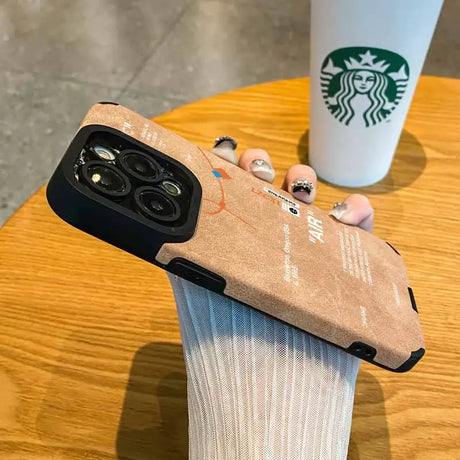 Someone holding a starbucks cup and a phone case on a table