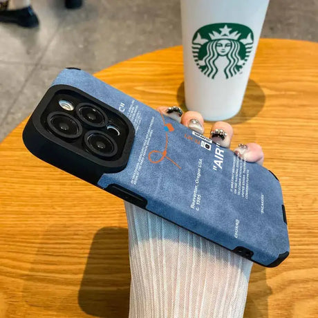 Someone holding a starbucks cup and a phone case on a table