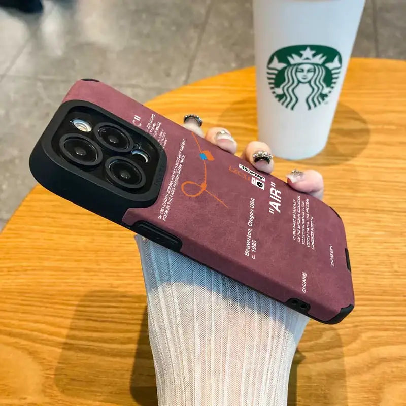 someone holding a starbucks cup and a phone case on a table