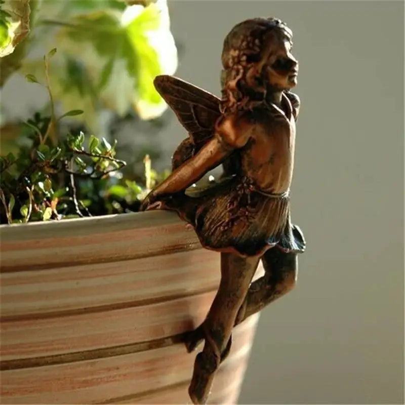 a small statue of a fairy sitting on top of a pot