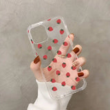a woman holding a clear phone case with strawberrys on it