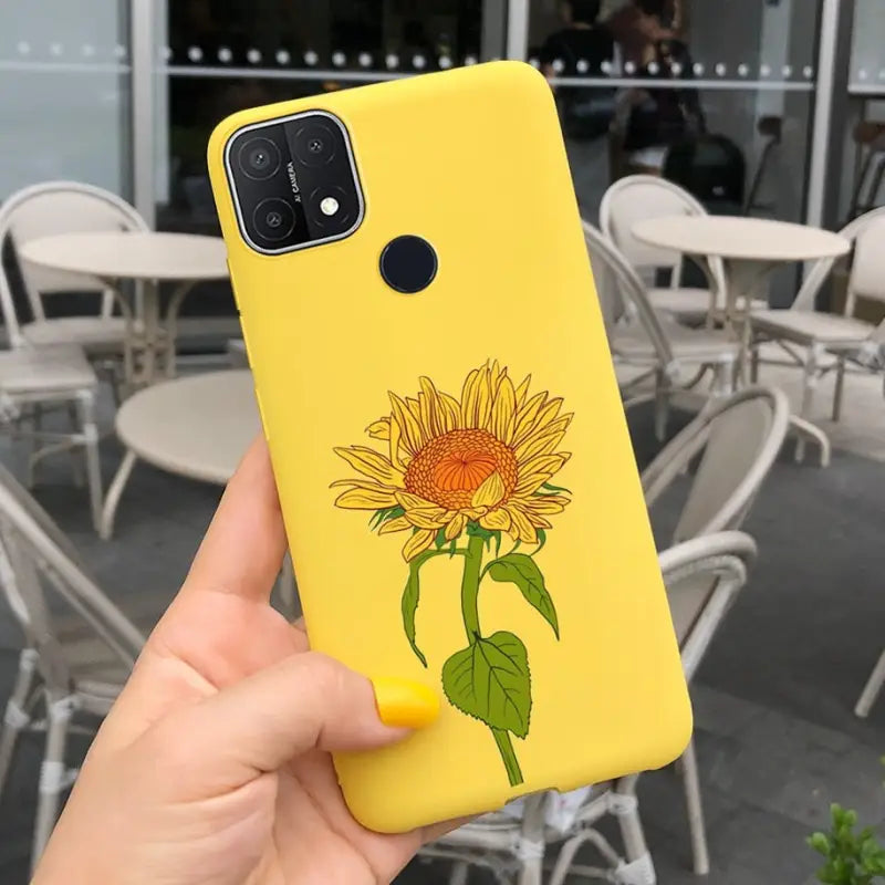 a person holding up a yellow phone case with a sunflower on it