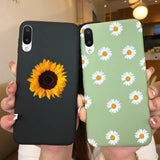 a woman holding up two iphone cases with sunflowers on them