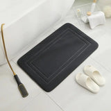 a black bath mat with a brush and a pair of slippers