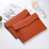 a pair of orange leather envelopes on a white table