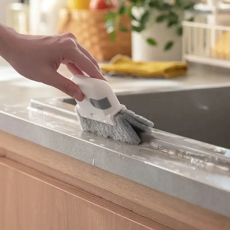 a person cleaning a kitchen counter with a brush