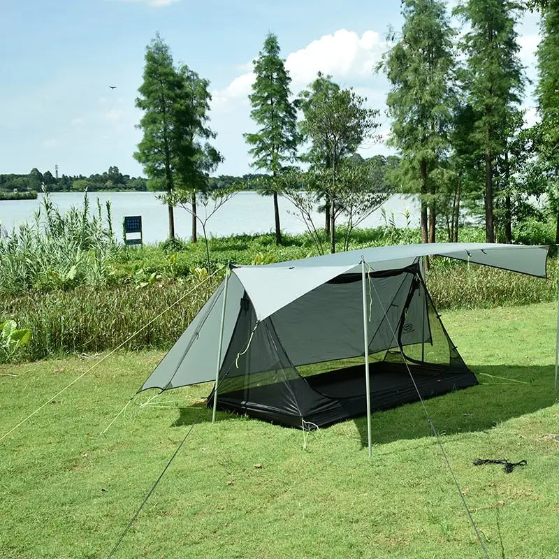 a tent is set up on the grass by the water