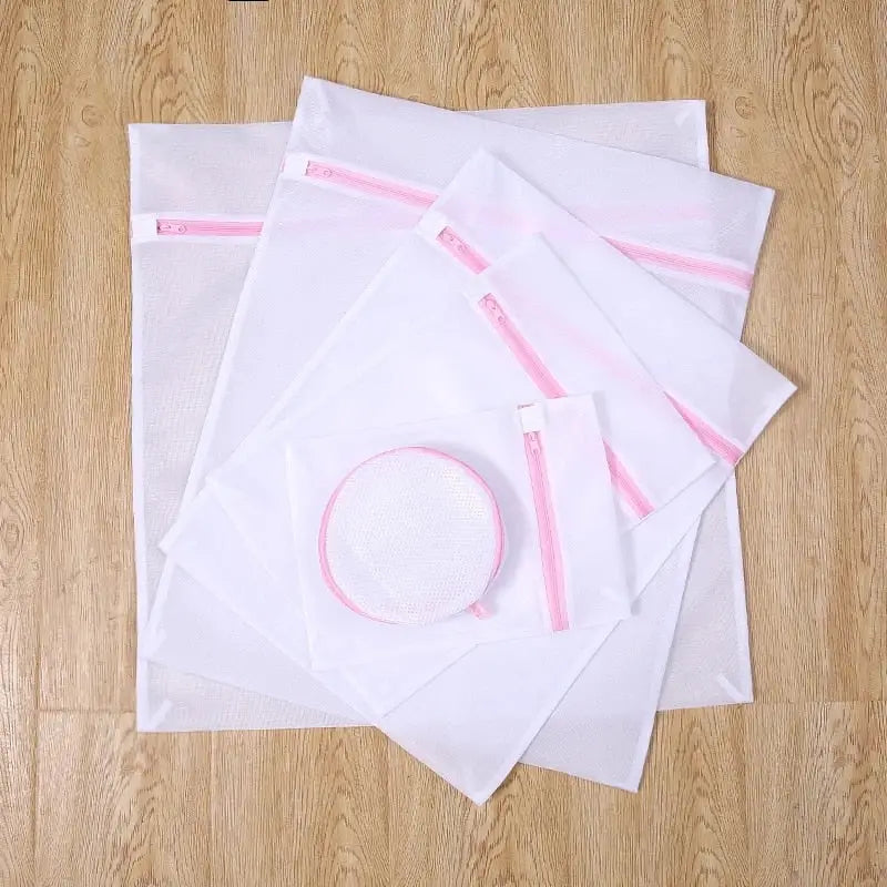 there are four bags of white paper with pink zippers on them