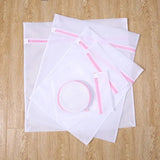 there are four bags of white paper with pink zippers on them
