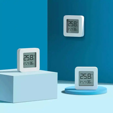 Three clocks on a stand in a room with a blue wall